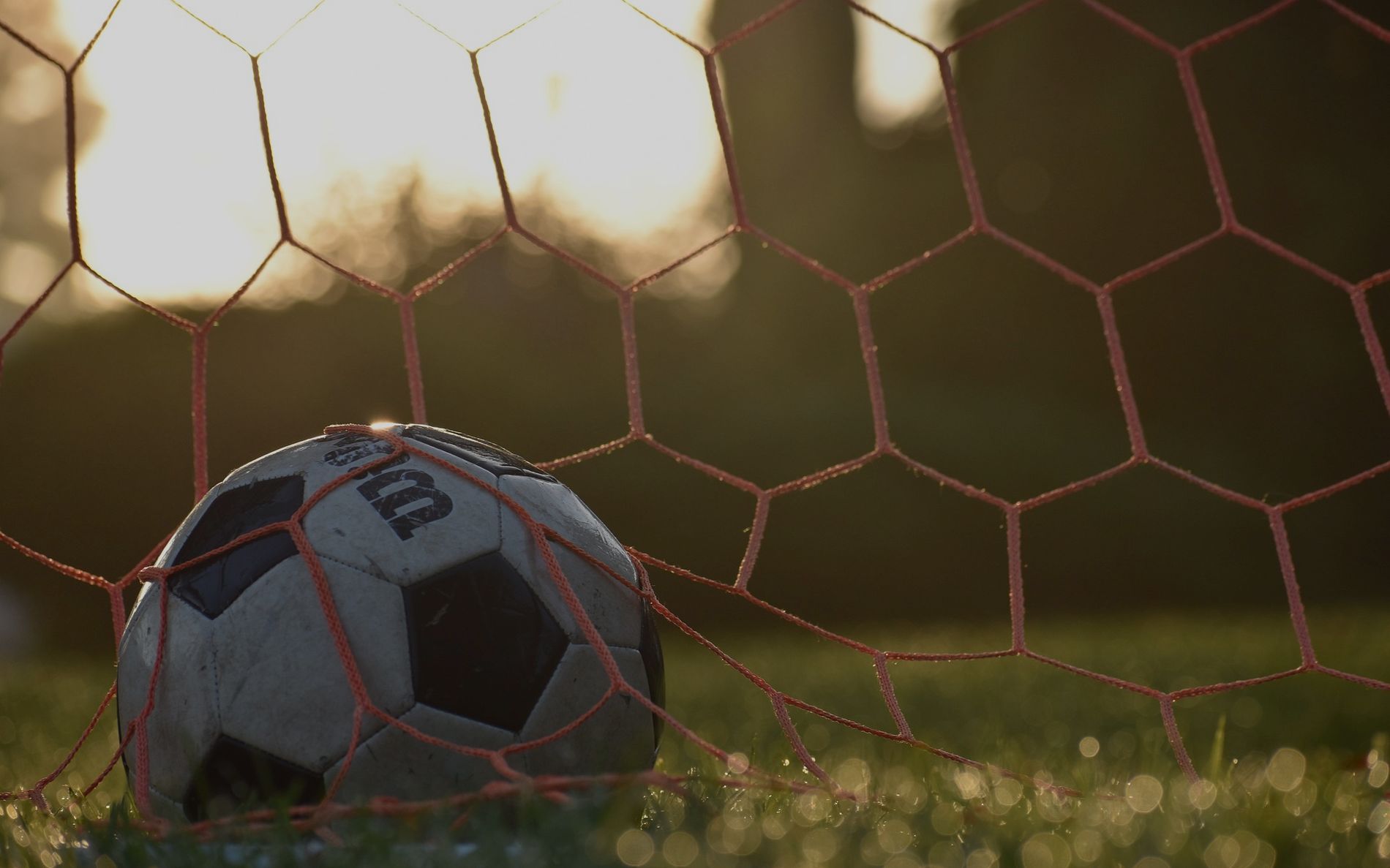 Pelota de futbol en la red al atardecer